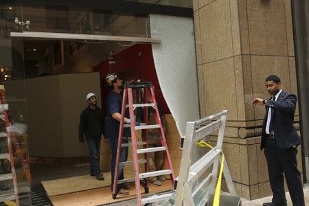 A security guard looks at his watch as workers remove shattered glass from the entrance to the Wells Fargo History Museum in San Francisco, California January 27, 2015. REUTERS/Robert Galbraith