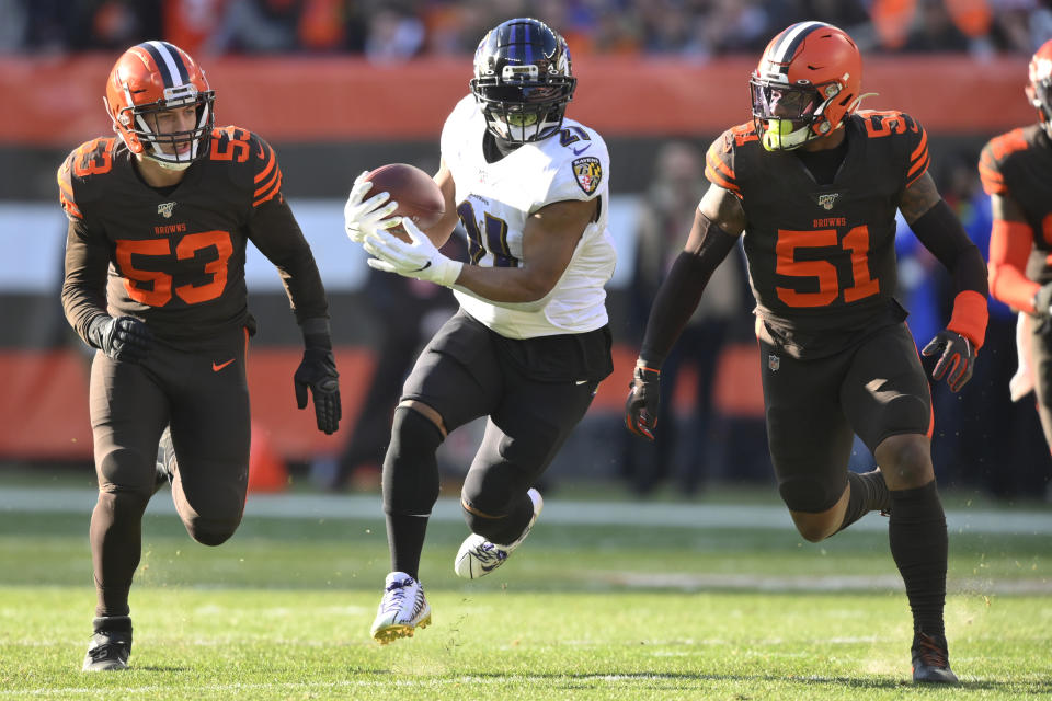 Baltimore Ravens running back Mark Ingram (21) rushes after a catch under pressure from Cleveland Browns middle linebacker Joe Schobert (53) and linebacker Mack Wilson (51) during the first half of an NFL football game, Sunday, Dec. 22, 2019, in Cleveland. (AP Photo/David Richard)