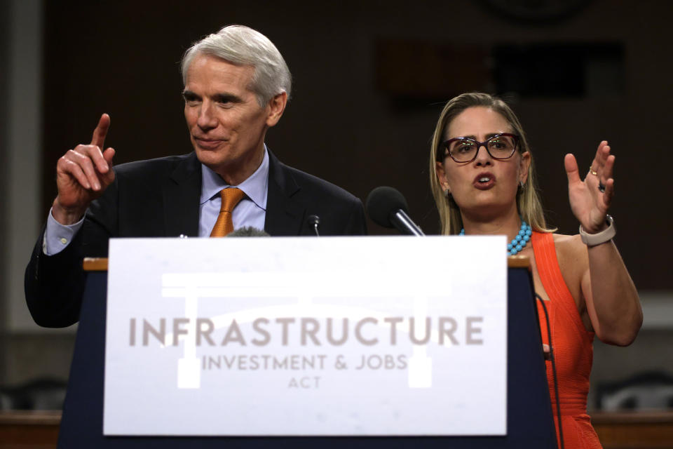 WASHINGTON, DC - JULY 28:  U.S. Sen. Rob Portman (R-OH) (L) and Sen. Kyrsten Sinema (D-AZ) (R) answer questions from members of the press during a news conference after a procedural vote for the bipartisan infrastructure framework at Dirksen Senate Office Building July 28, 2021 on Capitol Hill in Washington, DC. The Senate has advanced the bipartisan infrastructure framework with the vote of 67-32. (Photo by Alex Wong/Getty Images)