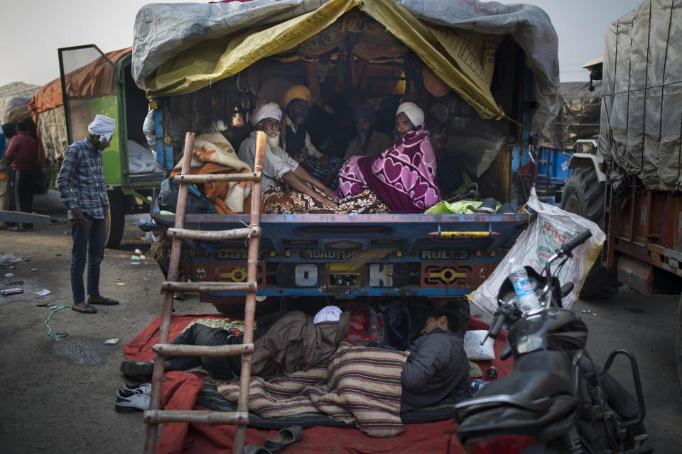 FILE - In this Tuesday, Dec. 1, 2020, file photo, Indian farmers huddle together in the back of their tractor trailer early morning as they protest against new farm laws, at the Delhi-Haryana state border, India. The protests gained momentum in November when the farmers tried to march into New Delhi but were stopped by police. Since then, they have promised to hunker down at the edge of the city until the laws are repealed. (AP Photo/Altaf Qadri, File)