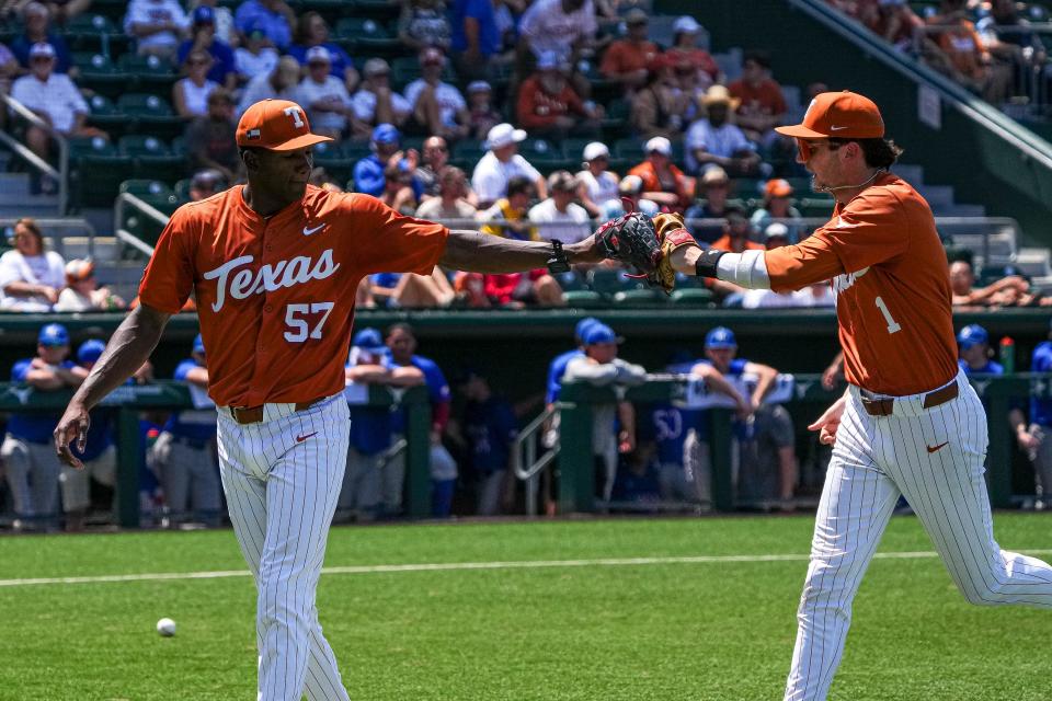 Texas pitcher Lebarron Johnson Jr. bumps gloves with infielder Jalin Flores after the third out of an inning during Saturday's 9-7 win over Kansas.