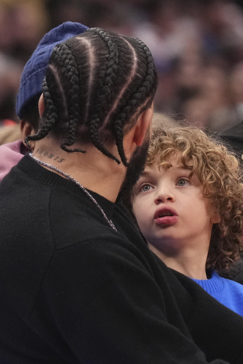 Adonis Graham, right, looks up at his father Drake as the Toronto Raptors take on the Phoenix Suns in an NBA basketball game in Toronto on Wednesday, Nov. 29, 2023. (Chris Young/The Canadian Press via AP)