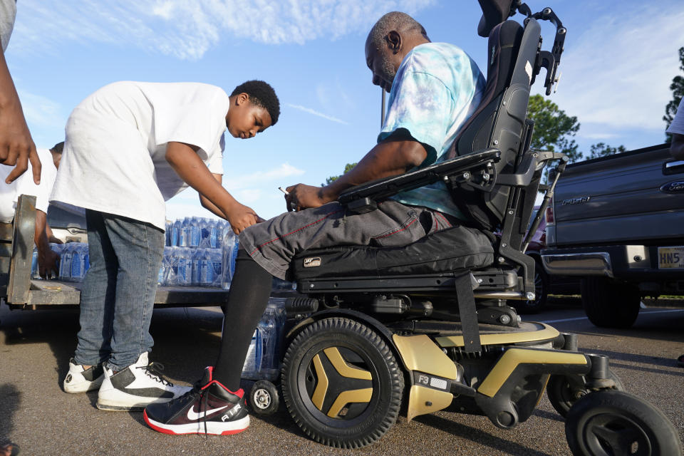 Earl O'Banner, a resident of the Golden Keys Senior Living Apartments gets a couple of cases of water placed on his chair in Jackson, Miss., Thursday, Sept. 1, 2022. A recent flood worsened Jackson's longstanding water system problems. (AP Photo/Steve Helber)