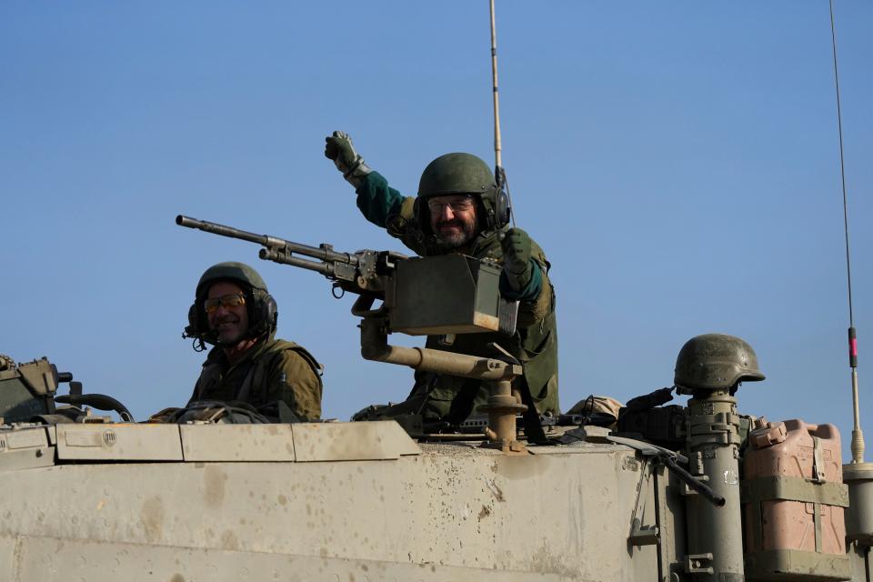 Israeli soldiers wave from a tank near the border between Gaza and southern Israel on Tuesday, Dec. 12, 2023.