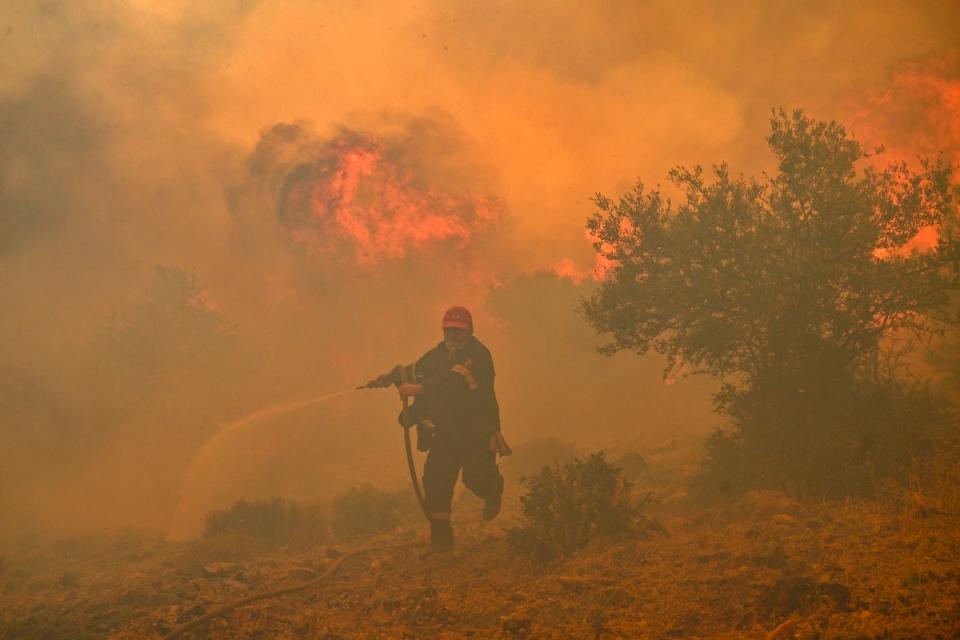 A fireman runs away from blazes as he tries to control a wildfire in New Peramos, near Athens (AFP via Getty Images)