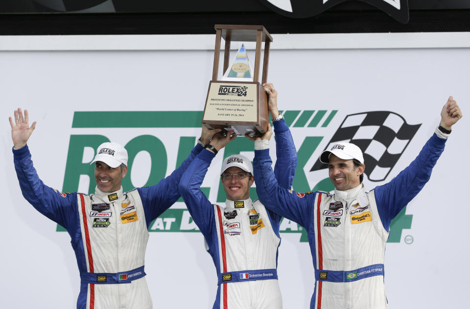 The Action Express team, from left, Joao Barbosa, of Portugal, Sebastien Bourdais, of France, and Christian Fittipaldi, of Brazil, celebrate with their trophy in Victory Lane after winning the IMSA Series Rolex 24 hour auto race at Daytona International Speedway in Daytona Beach, Fla., Sunday, Jan. 26, 2014.(AP Photo/John Raoux)