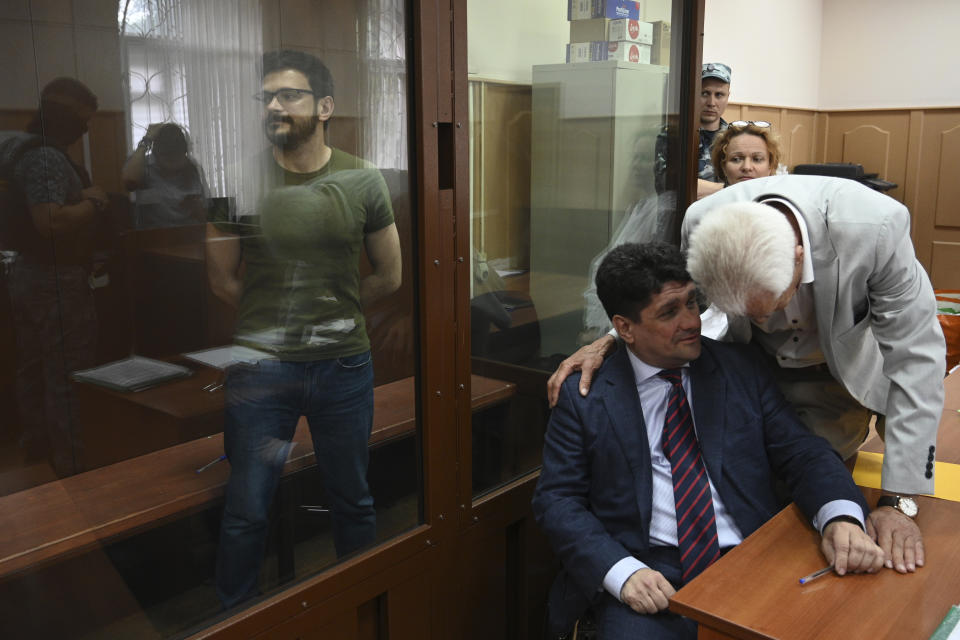 Russian opposition activist and a municipal deputy of the Krasnoselsky district Ilya Yashin, left, stands in a cage at a court room during a hearing on his detention the Basmanny district court in Moscow, Russia, Wednesday, July 13, 2022. Yashin faces charges under a new law making it a crime to spread false information about the military that carry a potential sentence of up to 15 years in prison. (AP Photo/Dmitry Serebryakov)