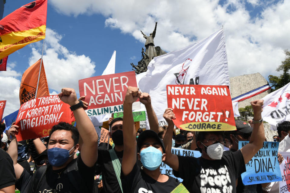 Protesters raise clinched fists as they hold banners with anti-Marcos slogans during a demonstration to commemorate the 36th anniversary of the People Power Revolution in 1986 that ousted the late dictator Ferdinand Marcos, in front of the People Power monument in Quezon City, suburban Manila on Feb. 25, 2022.<span class="copyright">Ted Aljibe—AFP/Getty Images</span>