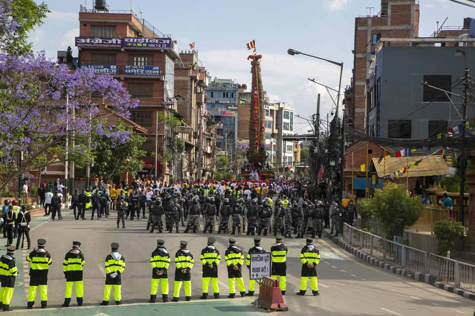 Policemen stand guard as Nepalese devotees pull a chariot during the Rato Machindranath chariot festival in Lalitpur, Nepal, Saturday, May 15, 2021. A truncated version of a Hindu chariot festival took place in Nepal's capital on Saturday amid strict COVID-19 restrictions, following an agreement between organizers and authorities that prevented a repeat of violent confrontations between police and protesters at last year's festival. (AP Photo/Niranjan Shrestha)