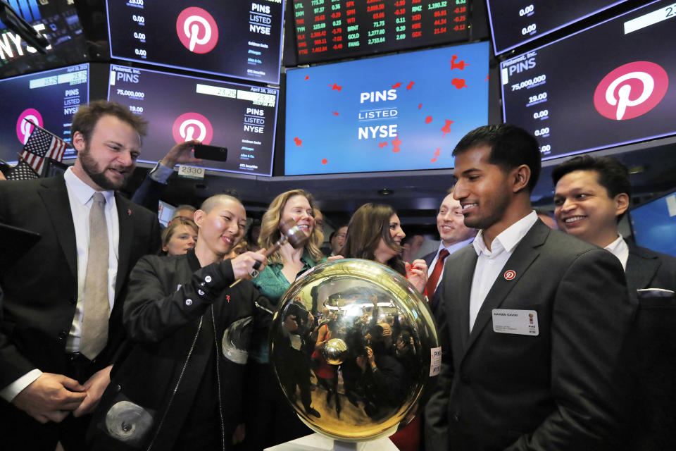 CORRECTS SPELLING FROM HUANG TO HWANG- Pinterest co-founder and chief product officer Evan Sharp, left, and fellow co-founder & CEO Ben Silbermann, right, watch as company Communications Manager Enid Hwang rings a ceremonial bell when their IPO begins trading on the New York Stock Exchange floor, Thursday, April 18, 2019. (AP Photo/Richard Drew)