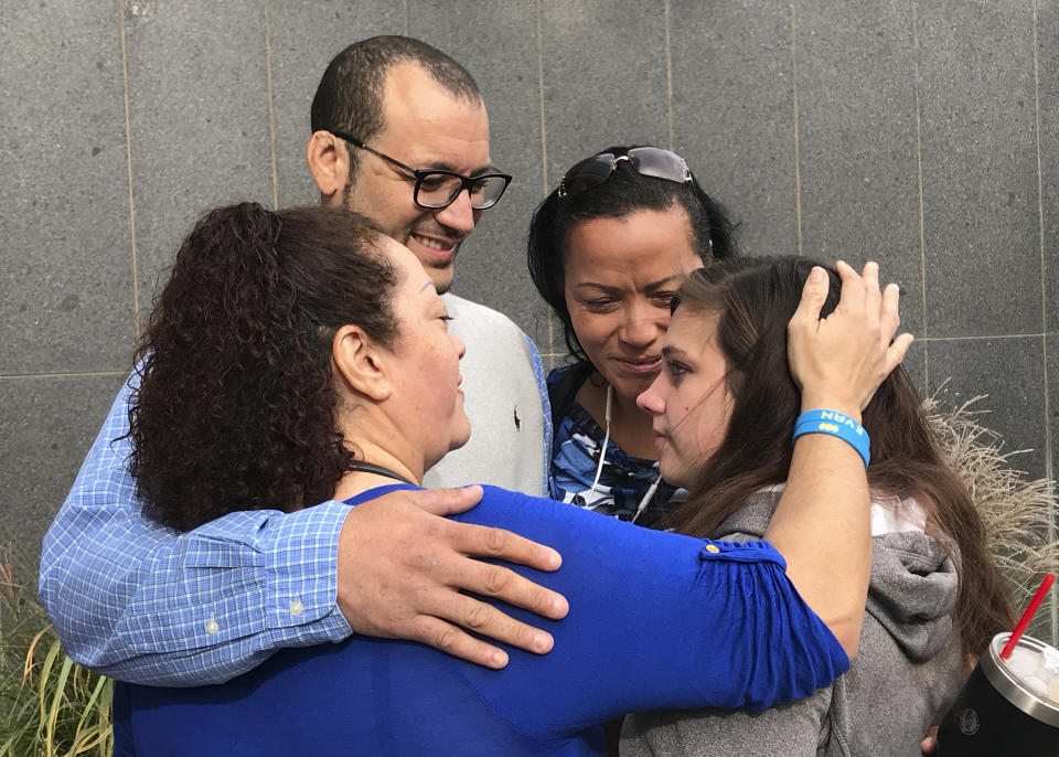 Carlo Brewer and his sisters Carol Brewer, left, Cheryl Brewer, center, embrace Samantha Johnson, the daughter of Steven Bodine. Bodine was convicted Wednesday, Oct. 24, 2018, in Wichita, Kan., in the murder of three-year-old Evan Brewer, Carlo's son. Johnson became connected with the Brewers after suffering child abuse at the hands of her father Steven Bodine. (Amy Leiker/The Wichita Eagle via AP)