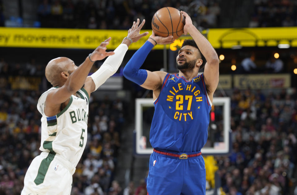 Denver Nuggets guard Jamal Murray, right, shoots for a 3-point basket over Milwaukee Bucks guard Jevon Carter in the first half of an NBA basketball game Saturday, March 25, 2023, in Denver. (AP Photo/David Zalubowski)