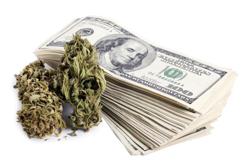 Marijuana buds sitting next to a stack of $100 bills.