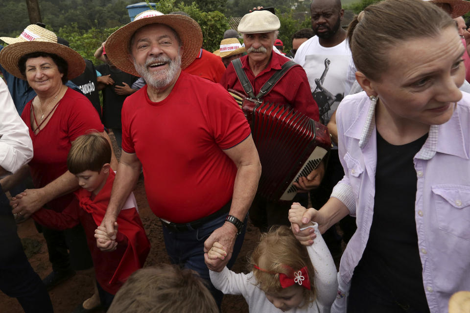 FILE - Brazil's former President Luiz Inacio Lula da Silva walks with supporters during a rally on a farm in Nova Erechim in southern Brazil, March 25, 2018. Brazil’s President Jair Bolsonaro is betting on a program crafted to distribute land ownership to thousands of rural farmers as a tool to win over some countryside voters and beat Luiz Inacio Lula da Silva in the oct. 2, 2022 election. (AP Photo/Eraldo Peres, File)