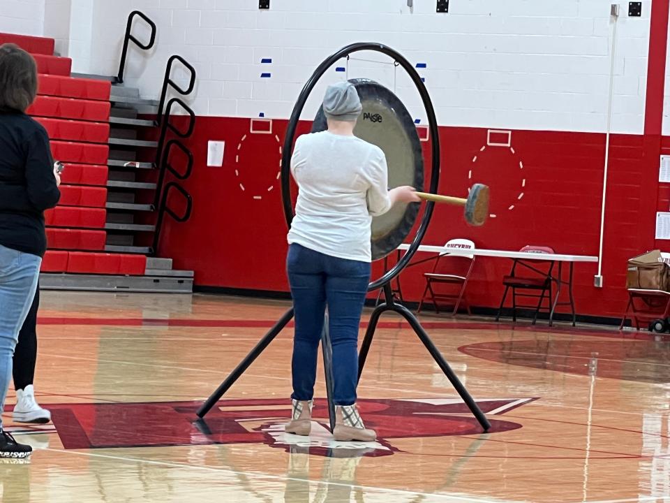 Bucyrus High School secretary Fran Swavel sounds a gong three times, just as cancer patients ring a bell when they have completed treatment, during a pep rally in her honor at Bucyrus High School on Tuesday.