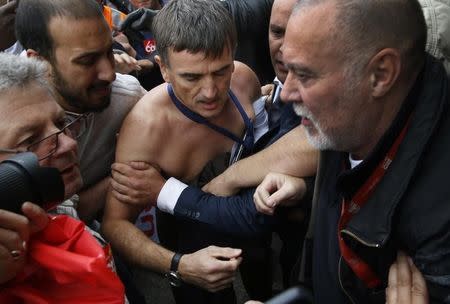 A shirtless Xavier Broseta (C) is evacuated by security after employees interrupted a meeting with representatives staff at the Air France headquarters building at the Charles de Gaulle International Airport in Roissy, near Paris, France, October 5, 2015. REUTERS/Jacky Naegelen