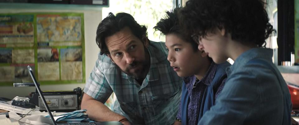 Paul Rudd, young boy with spiked hair, and young girl with curly hair in casual clothing looking at a laptop screen in a scene from a TV show or movie