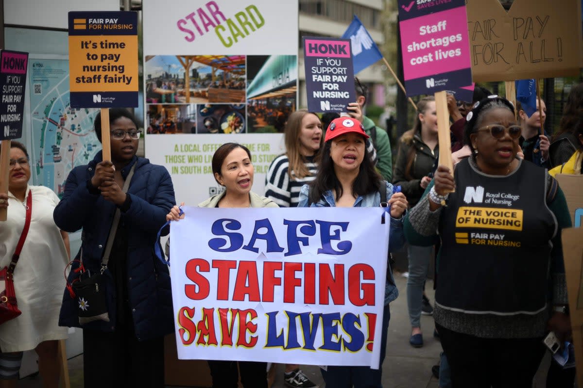 Healthcare workers hold placards as they demonstrate outside St Thomas' Hospital in London (AFP via Getty Images)