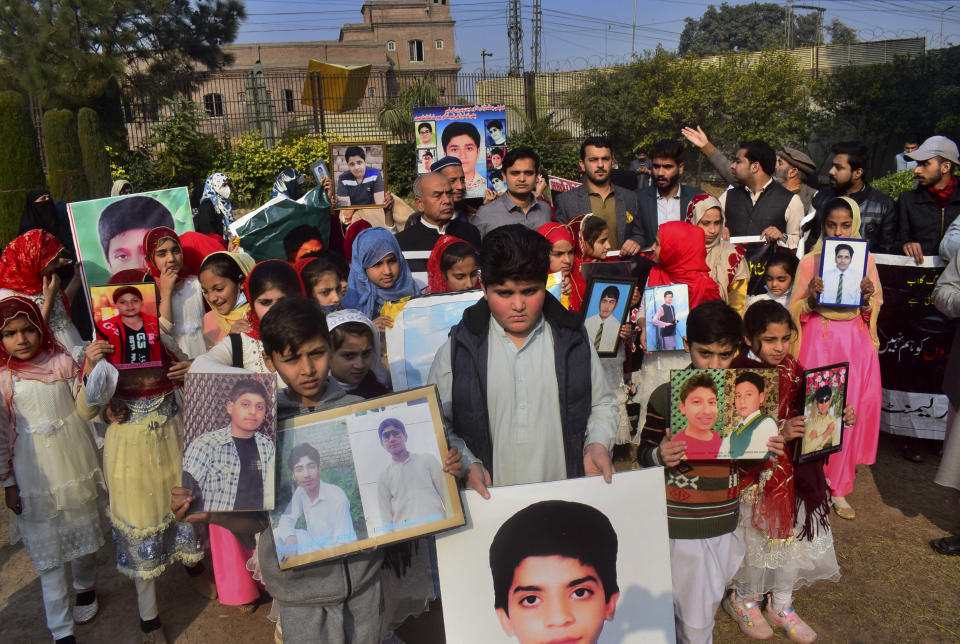Pakistani families hold portraits of their loved ones, who were killed in a 2014 assault by Pakistani Taliban militants on an army public school that killed 150 people, during a ceremony to pay tribute to them, in Peshawar, Pakistan, Dec. 14, 2021. Even as Pakistan leads the effort to get a reluctant world to engage with Afghanistan, the Taliban rulers have shown no sign of expelling multiple militant groups operating on its soil, and that it raising a dilemma for other nations as they ponder how to deal with them. (AP Photo/Muhammad Sajjad)