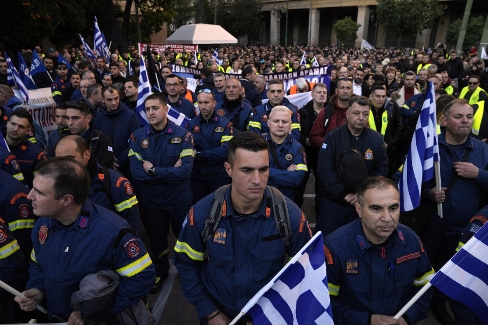 Firefighters holding Greek flags join a protest by uniformed officers in Athens, Greece, Monday, Dec. 18, 2023. About 1,500 people took part in the rally, organized by police, firefighters and coast guard unions in response to the non-legalization of their profession as hazardous. (AP Photo/Thanassis Stavrakis)