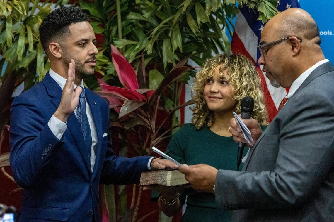 Newly appointed Broward County School Board Member Daniel P. Foganholi, left, is sworn in by Attorney Levi G. Williams Jr., right, as Alyssa Foganholi, center, holds the family Bible during a special ceremony at the Kathleen C. Wright Administration Center in Fort Lauderdale, Florida, on Jan. 18, 2023.