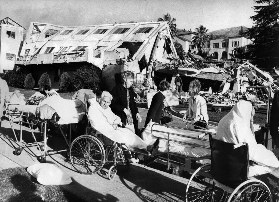 Patients sit just outside a collapsed hospital building