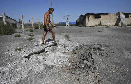 A local resident walks past a crater caused by shelling in the village of Spartak outside Donetsk, September 3, 2014. REUTERS/Maxim Shemetov