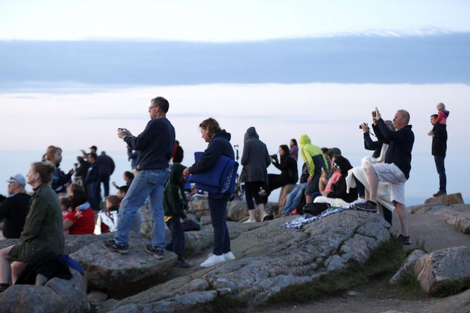 People with cameras look out over the sea