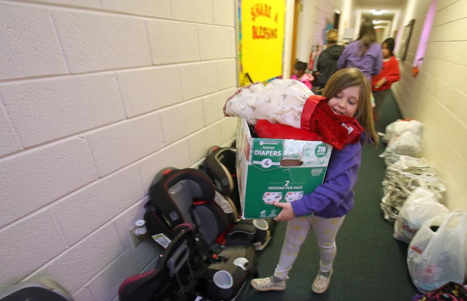 Eight-year-old Willow Davis helps carry a box of items for a family in need Saturday morning, Nov. 20, 0221, at the infant and toddler clothing closet at Polkville Baptist Church.