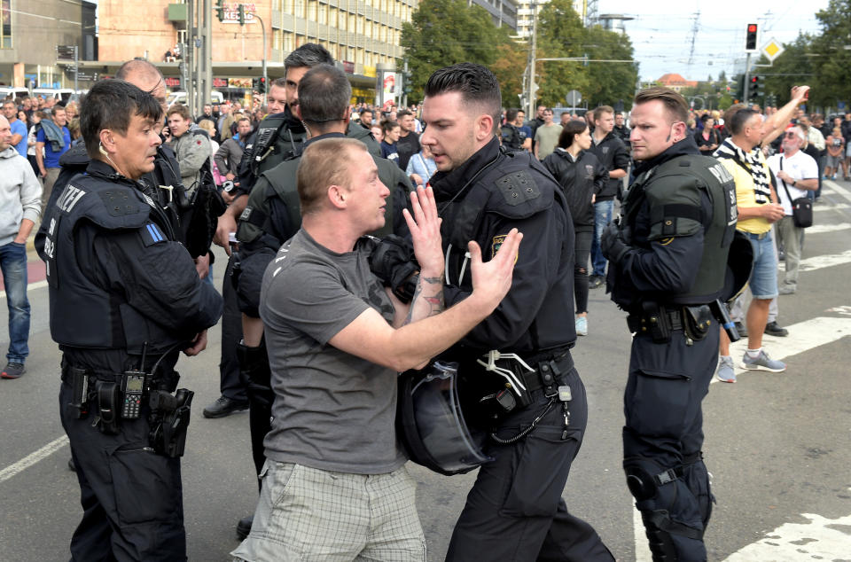 A police officer pushes a man during a demonstration in Chemnitz, Germany, Monday, Aug. 27, 2018 after a man has died and two others were injured in an altercation between several people of "various nationalities" in the eastern German city of Chemnitz on Sunday. Slogan reads 'No Access For Terror'. (AP Photo/Jens Meyer)