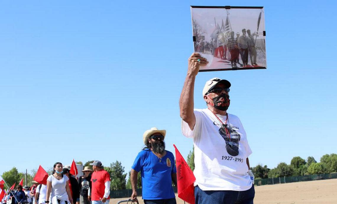 Roberto Bustos was in charge of the UFW's historic 1966 Delano-to-Sacramento march. He sports a photo of that march while attending the start of another march at Forty Acres on Aug. 3, 2022.