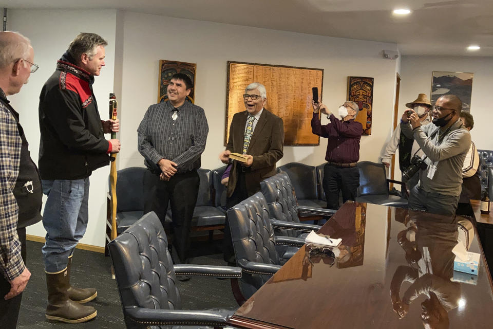 Metlakatla Indian Community Mayor Reginald Atkinson, fourth from left, laughs as he presents gifts to Alaska Gov. Mike Dunleavy on Thursday, April 22, 2021, in Metlakatla, Alaska. Dunleavy is shown second from left, holding a talking stick he was given as a gift. (AP Photo/Becky Bohrer)