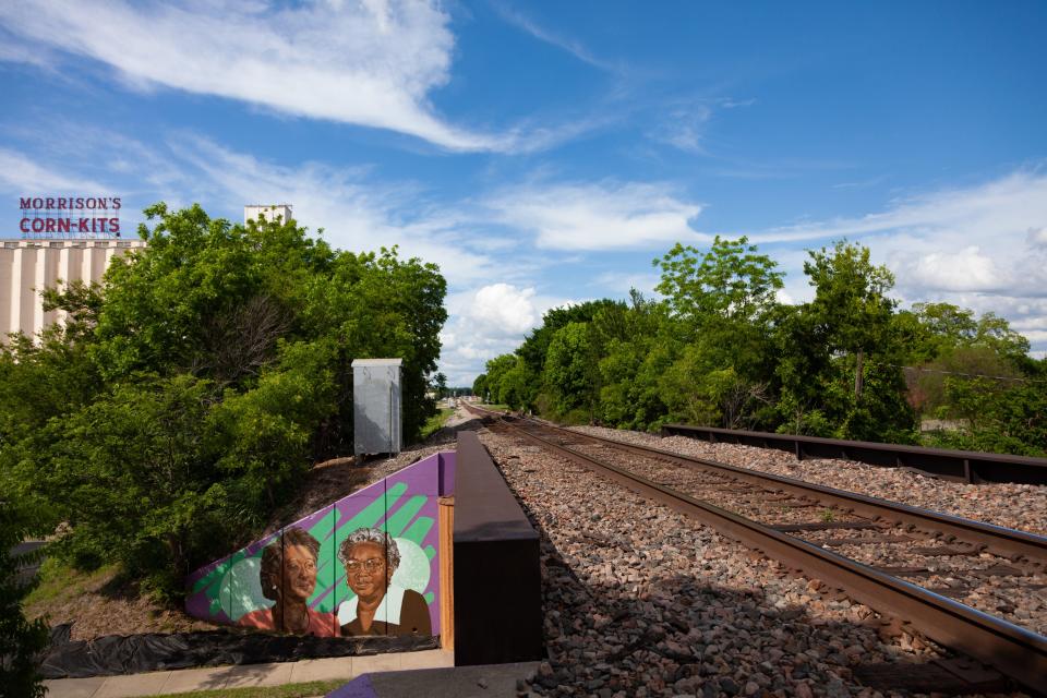 Train tracks, with a colorful mural to the side.