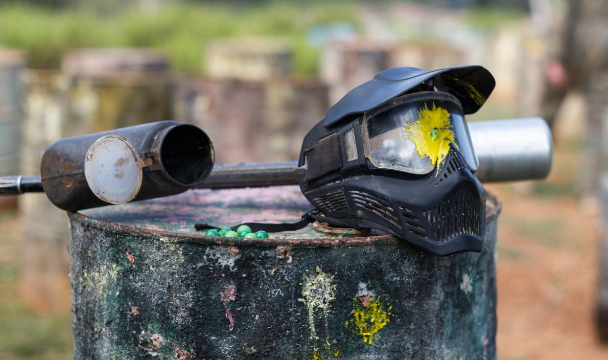 Closeup of black paintball mask with splash after direct hit from match outdoors