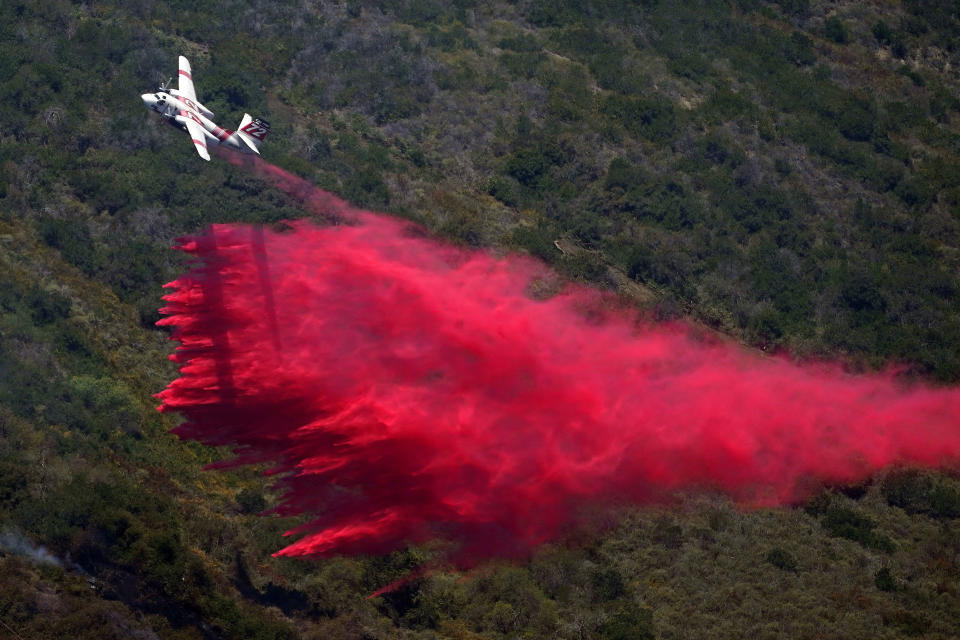 A plane drops fire retardant onto the Coastal Fire Thursday, May 12, 2022, in Laguna Niguel, Calif. (AP Photo/Marcio Jose Sanchez)
