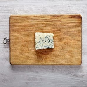 One piece of fresh roquefort cheese on wooden board