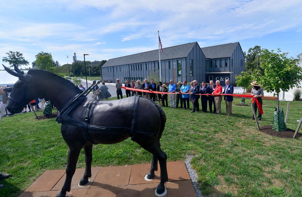 Local officials gather for a ribbon cutting ceremony in site of the canal mule statue, now named Paw Paw, outside the new C&O Canal headquarters in Williamsport.