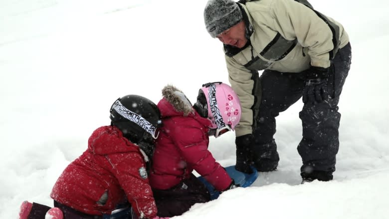 A man tries to pull his two children and the sled up the hill at Riverdale Park East in Toronto, Ont., on Sunday.
