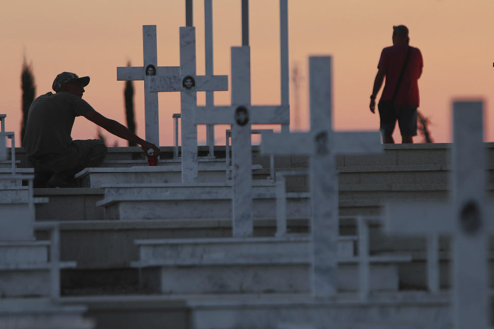 A soldier trims the graves of soldiers killed in the 1974 Turkish invasion of Cyprus, in the Tymvos Macedonitissas military cemetery during the 45th anniversary in the divided capital of Nicosia, Cyprus, Friday, July 19, 2019. Some thousands of Greek and Cypriot soldiers were killed in 1974 during the Turkish invasion on July 20, 1974 and subsequent occupation of the northern part of the island of Cyprus. (AP Photo/Petros Karadjias)