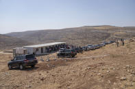 With Israeli settlement of Kokhav Hashahar in the background, European Union representatives visit a school structure that is under the threat of demolition by the Israeli authorities, in the West Bank Bedouin community of Ein Samia, northeast of Ramallah, Friday, Aug. 12, 2022. The Israeli District Court in Jerusalem issued on Wednesday, Aug. 10, a decision to immediately demolish the Ein Samia school. Fifty four schools serving seven thousand Palestinian children in the West Bank's area "C" are under threat of demolition, Sven Kuhn von Burgsdorff, the European Union's representative to the West Bank and Gaza told reporters. (AP Photo/Nasser Nasser)