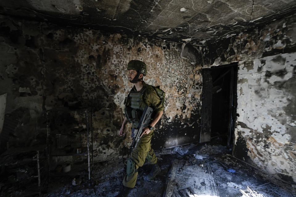 An Israeli soldier inspects a house damaged by Hamas militants in Kibbutz Kfar Azza, Israel, Wednesday, Oct. 18, 2023. The Kibbutz was overrun by Hamas militants from the nearby Gaza Strip on Oct. 7, when they killed and captured many Israelis. (AP Photo/Ariel Schalit)