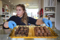 Niaz Mardan moves a tray of luxury handmade Belgian chocolates at Sandrine a chocolate shop in south west London, Thursday, March 21, 2024. Niaz Mardan, is suffering due to high cocoa prices, she's making no profits and fears she will have to close the shop that's been around for 25 years (she's the third owner and took over in 2019). (AP Photo/Kirsty Wigglesworth)