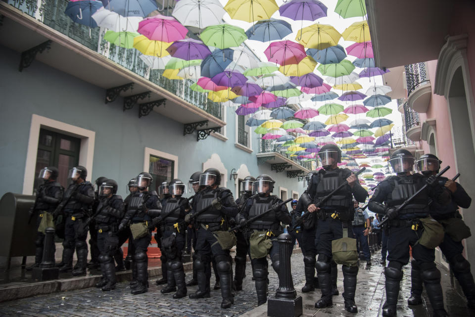 In this Sunday, July 14, 2019 photo, police block protesters from advancing to La Fortaleza governor's residence in San Juan, Puerto Rico. Protesters are demanding Gov. Ricardo Rosselló step down for his involvement in a private chat in which he used profanities to describe an ex-New York City councilwoman and a federal control board overseeing the island's finance. (AP Photo/Carlos Giusti)