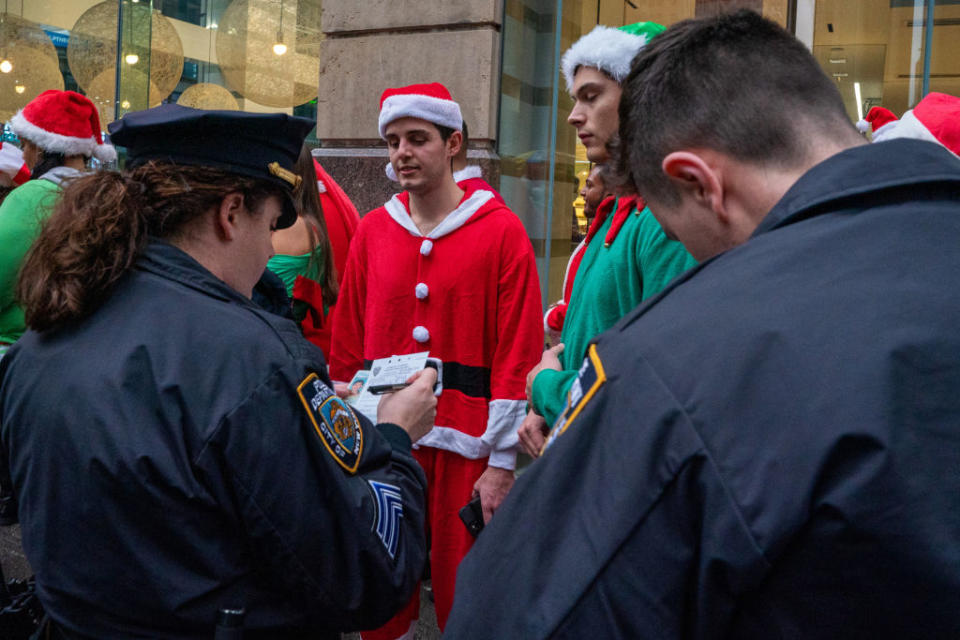 A person receives a citation for public drinking from NYPD officers during SantaCon in New York City. (Photo by David Dee Delgado/Getty Images)<br>