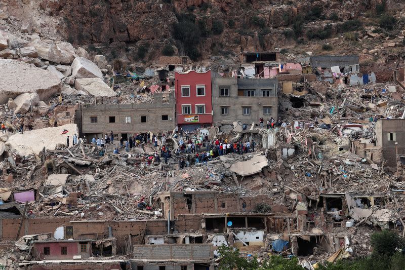 People stand on rubble in Imi N'Tala village, that was devastated by a deadly earthquake