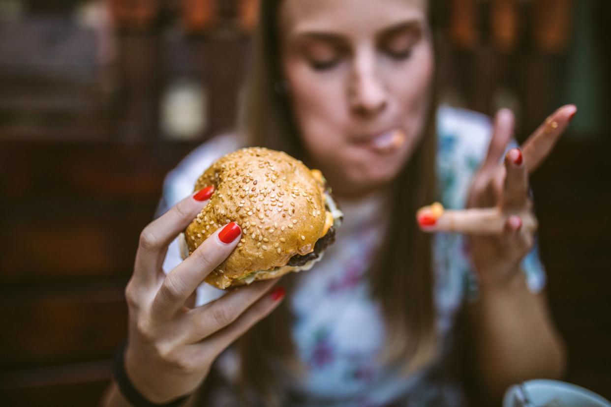 Gourmand Girl Eating Tasty Hamburger at Fast Food Restaurant