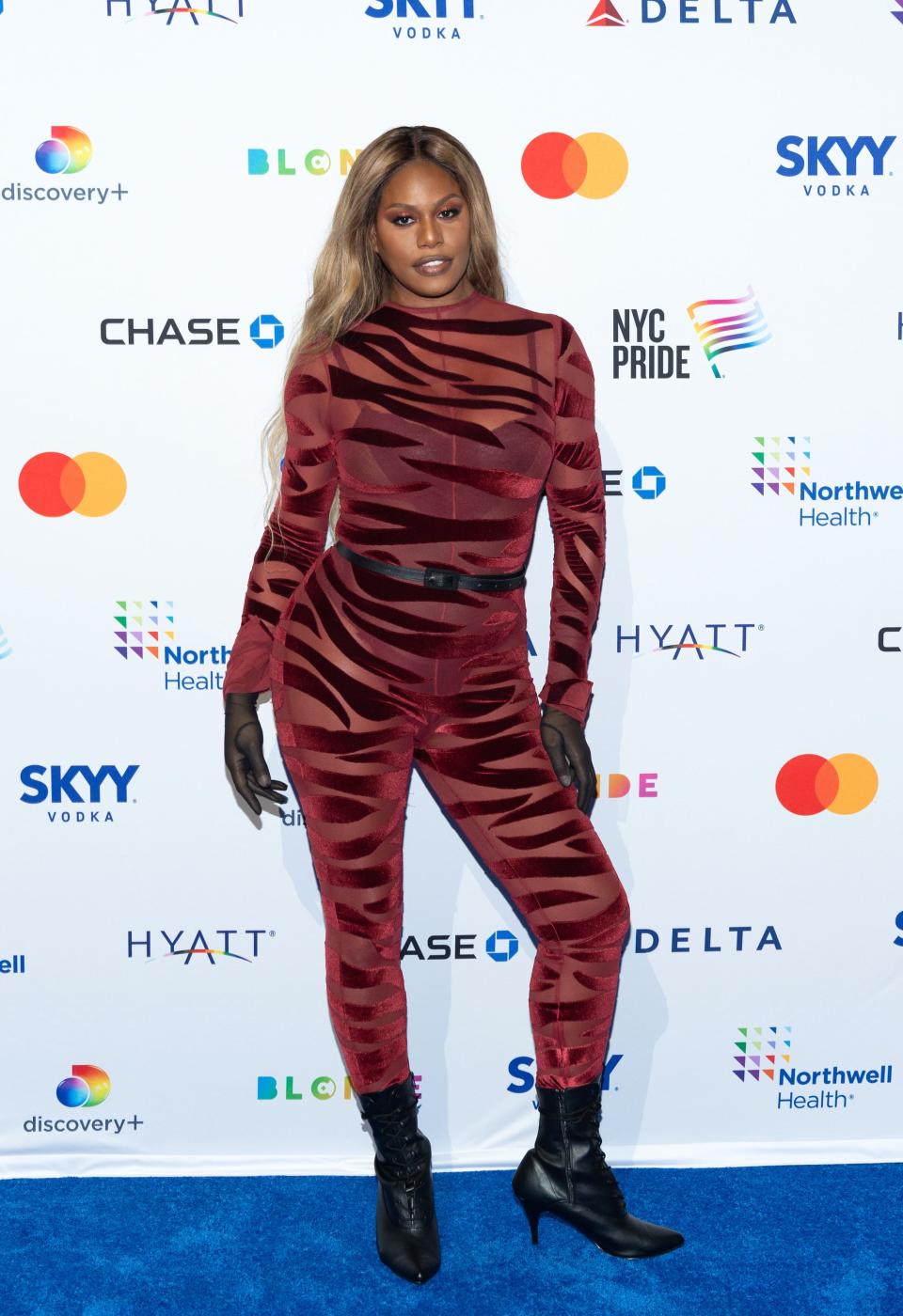 Laverne Cox in a red zebra print jumpsuit and black boots