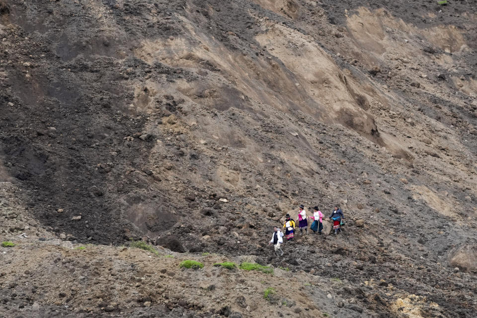 Residents walk in an area swept by a landslide in Alausi, Ecuador, Tuesday, March 28, 2023, the day after the avalanche buried dozens of homes. (AP Photo/Dolores Ochoa)