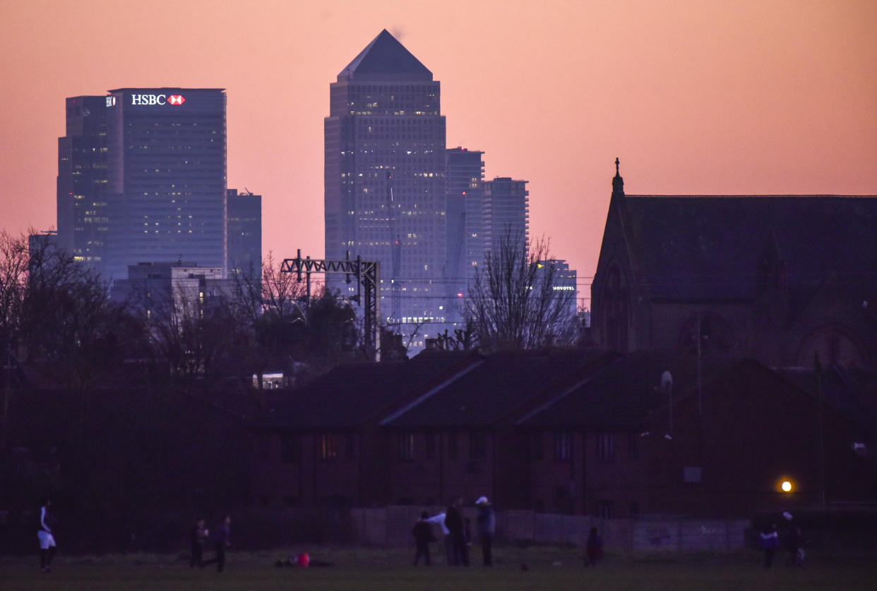 General view of the skyline of the Canary Wharf financial district as people play at Wanstead Flats at sunset, in London, Sunday, Feb. 28, 2021.(AP Photo/Alberto Pezzali)