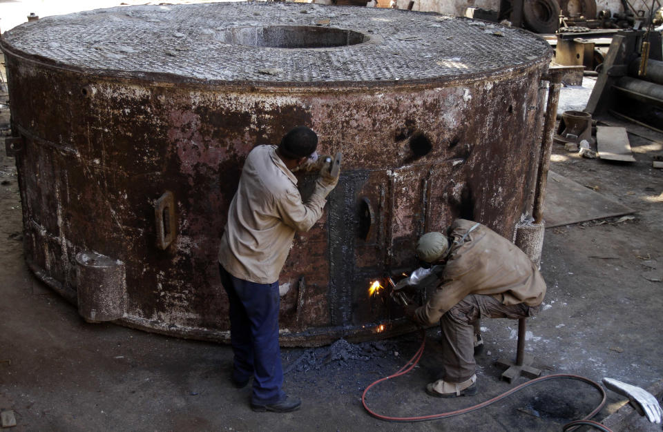 In this Sept. 8, 2012 photo, Juan Penalver 52, right, and Jorge Luis Piss, 39, repair a boiler where sugar cane syrup is cooked at the sugar processing plant "Brasil" in Jaronu, Cuba. The Brasil sugar plant, launched in 1921, is getting a makeover and is expected to be ready in time for the upcoming annual harvest and start milling cane by February. (AP Photo/Franklin Reyes)